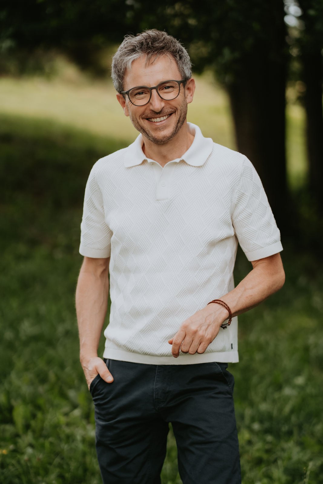 Porträt von Tobias Weise in der Natur – Der Energieweise, freundlich lächelnd auf einer Sommerwiese vor Bäumen